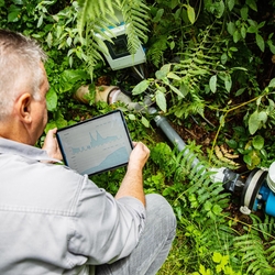 Man with flowmeter and tablet at a spring discharge